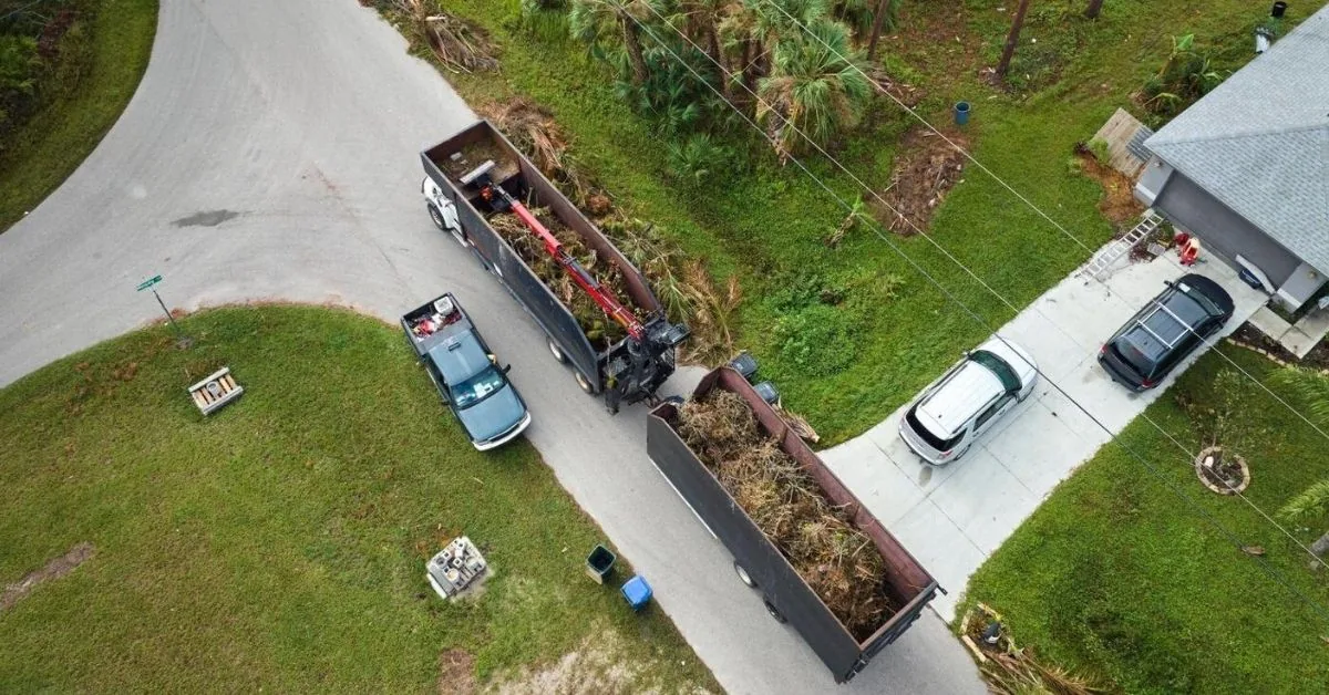 Aerial view of a truck and trailer loaded with brush beside a house